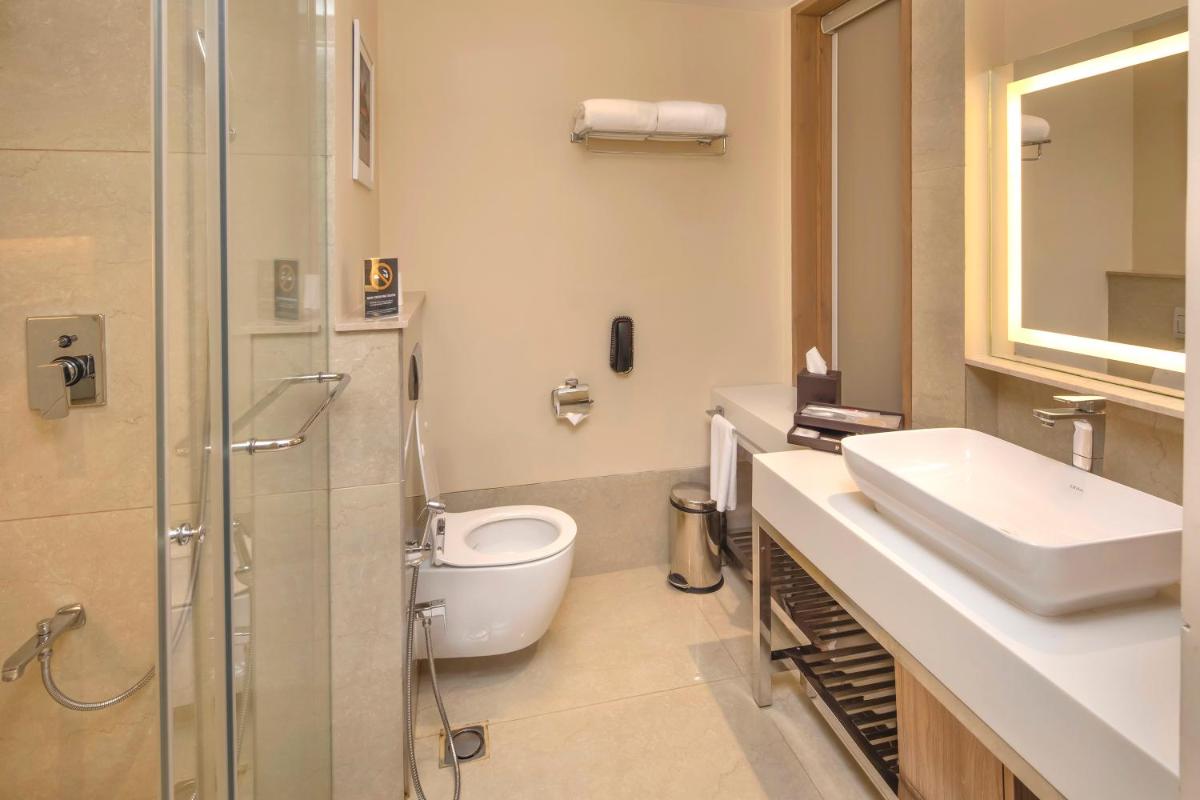 a bathroom with a toilet and a sink and a shower at O by Tamara, Trivandrum in Trivandrum