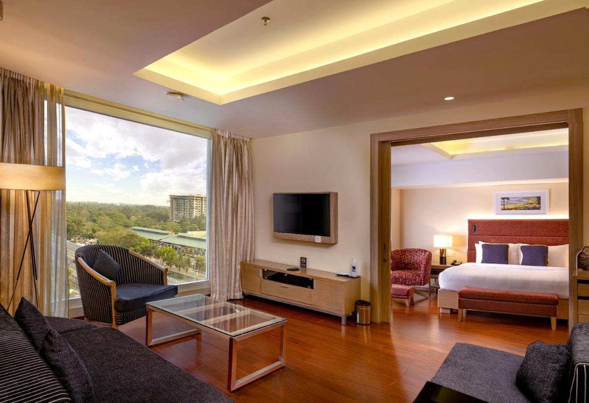 a hotel room with a bed and a large window at O by Tamara, Trivandrum in Trivandrum