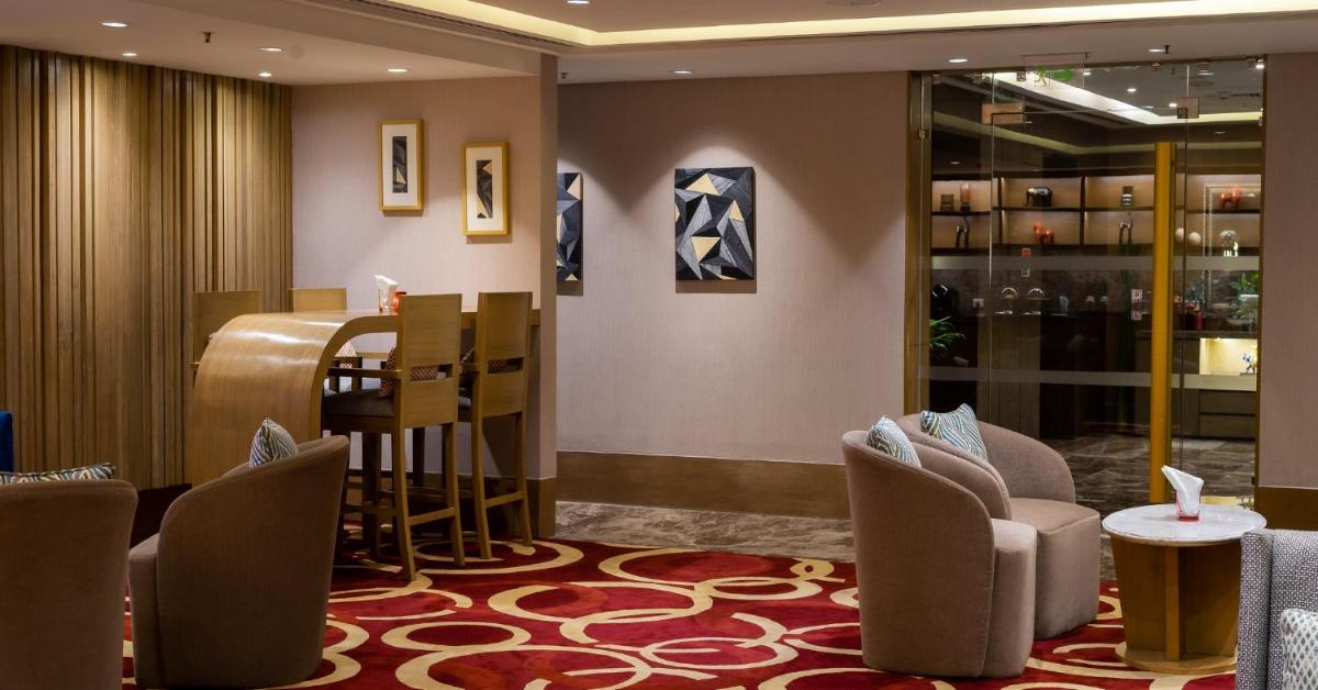 a lobby with chairs and a bar in a building at The Leela Ambience Convention Hotel Delhi in New Delhi