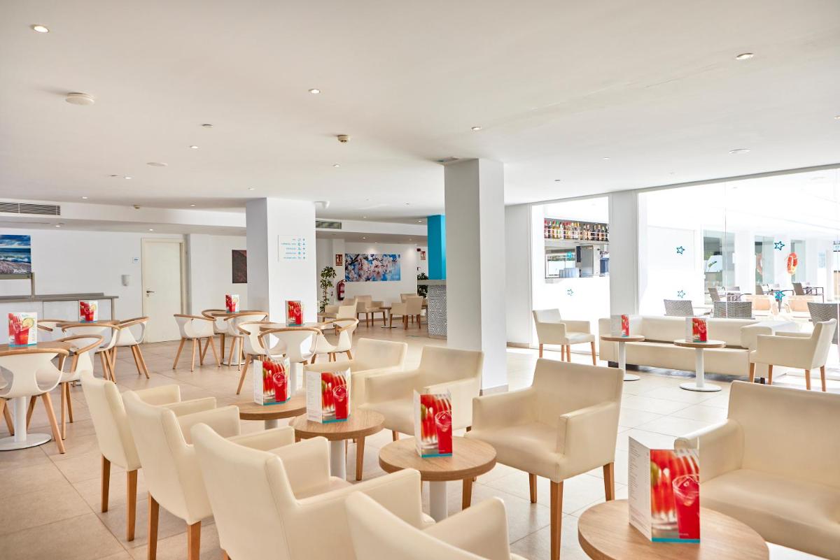 un restaurante con sillas y mesas blancas y arcos rojos en Hotel Ilusion Calma & Spa, en Can Pastilla