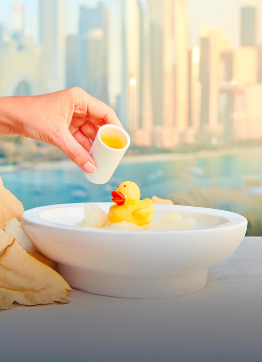 a person holding a cup of coffee with a rubber duck in a bowl at FIVE Palm Jumeirah Dubai in Dubai