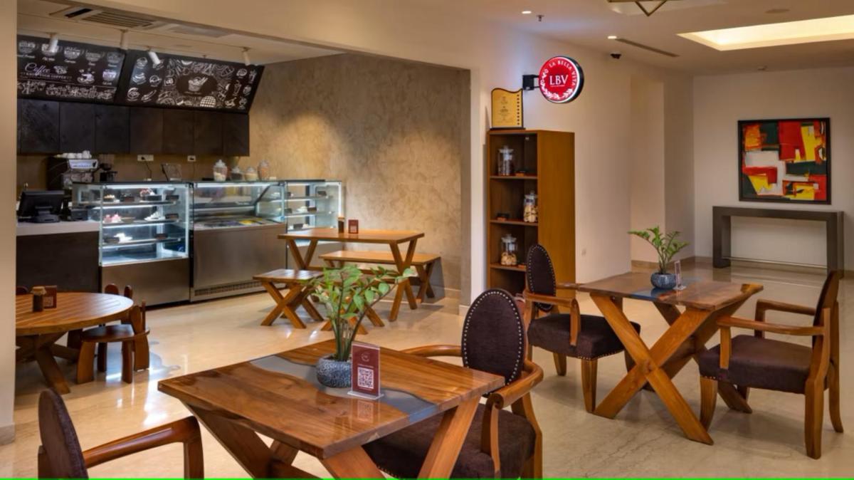 a restaurant with wooden tables and chairs and a kitchen at O by Tamara, Trivandrum in Trivandrum