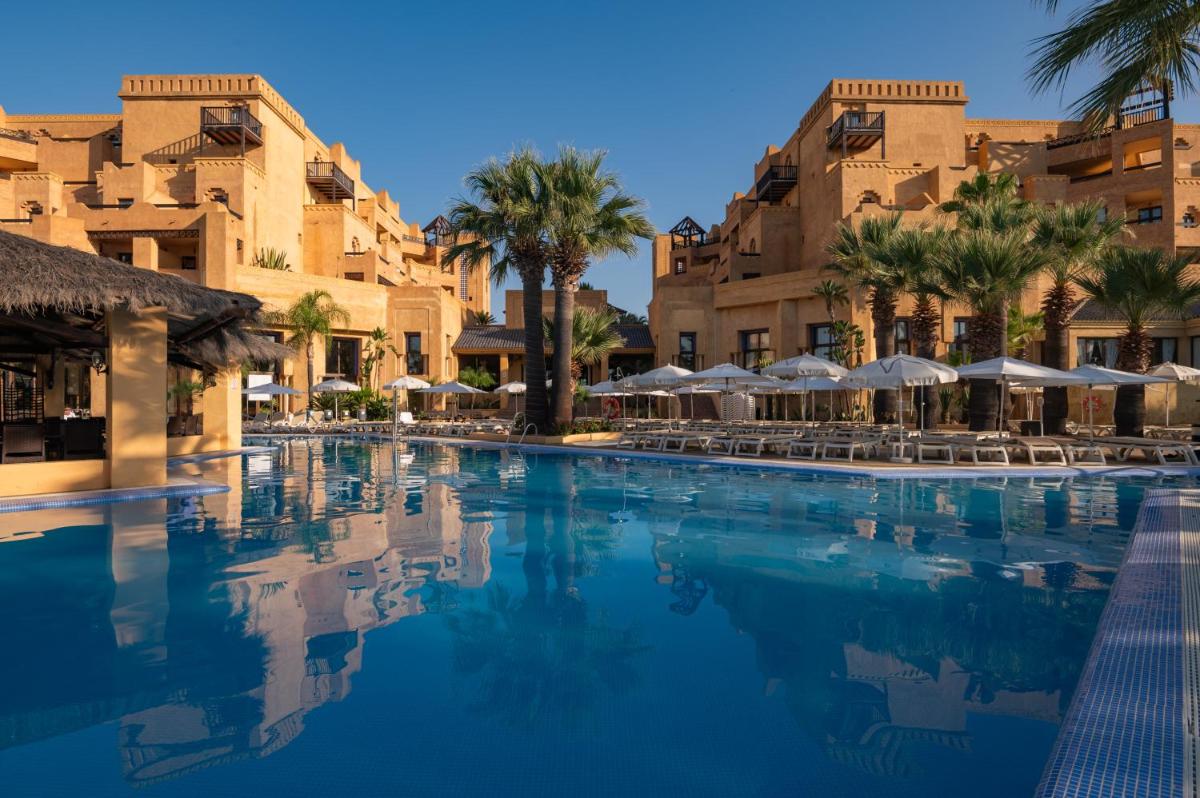 Una piscina en un resort con palmeras y sombrillas. en Vila Gale Isla Canela, en Isla Canela