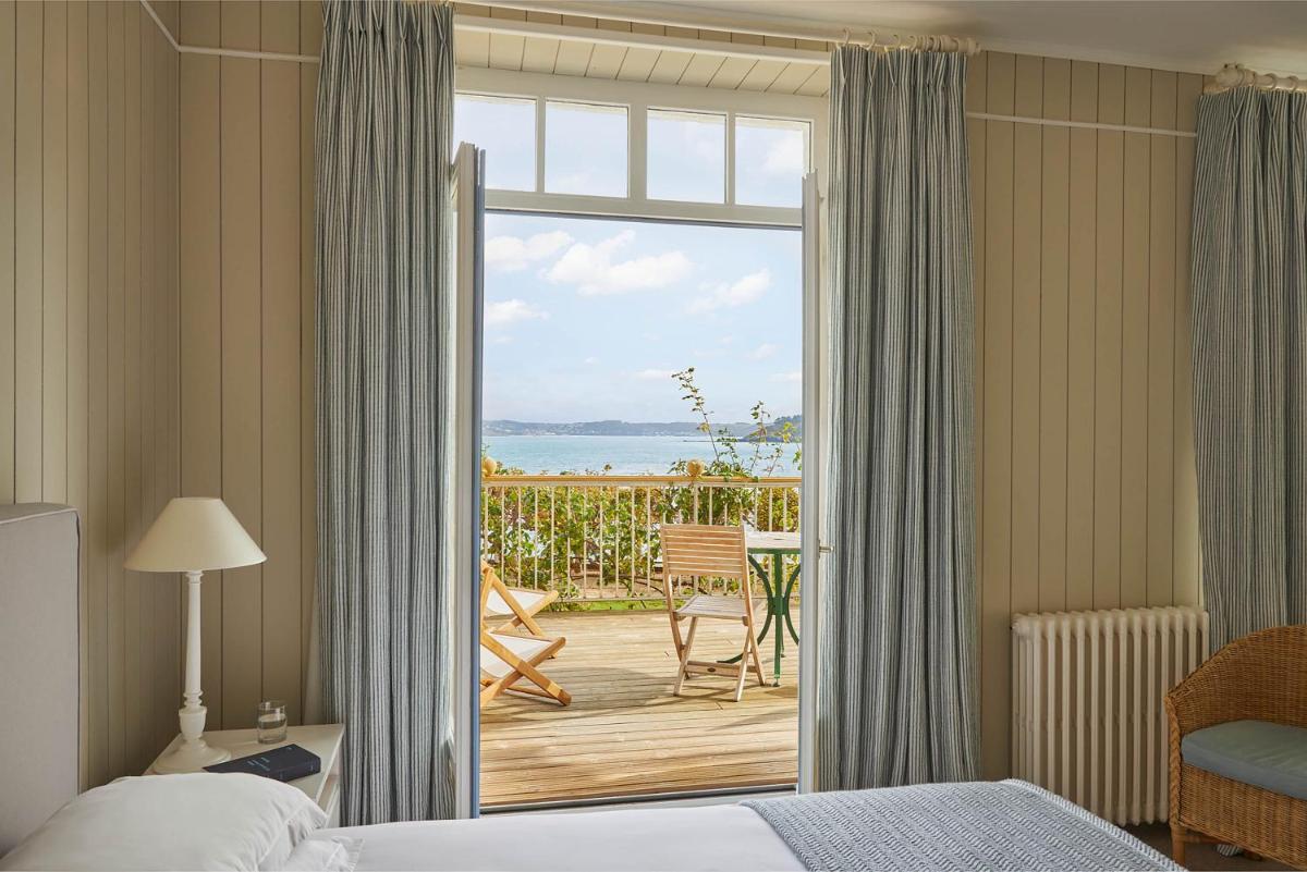 une chambre d'hôtel avec un lit et une porte coulissante en verre dans l'établissement Le Grand Hotel des Bains & Spa - Bretagne, à Locquirec