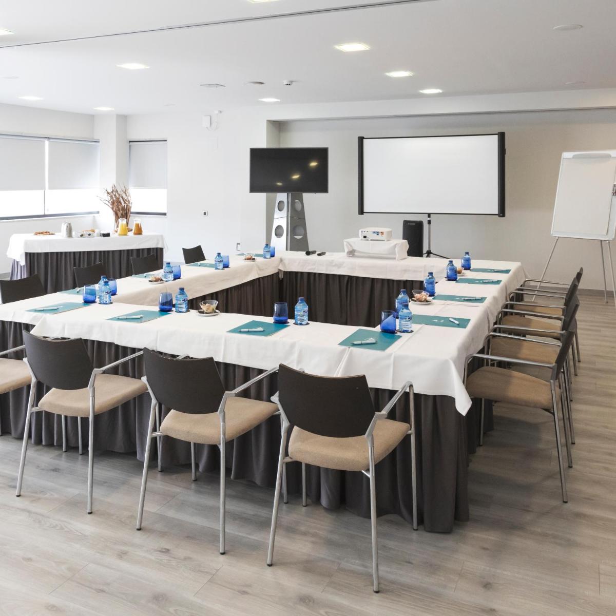 una sala de conferencias con mesas y sillas y una pantalla de proyección en Hotel & Spa Real Ciudad De Zaragoza, en Zaragoza 32 fotos más