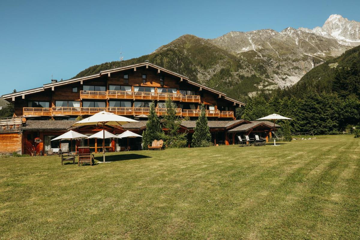 un grand bâtiment avec une pelouse devant lui dans l'établissement Les Grands Montets Hotel & Spa, à Chamonix-Mont-Blanc