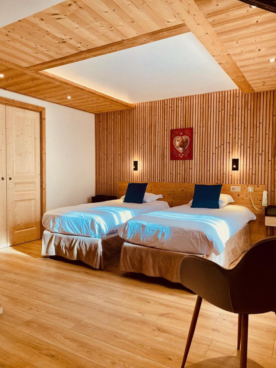 deux lits dans une chambre avec des murs et du parquet en bois dans l'établissement Hotel Alpina, à Morzine