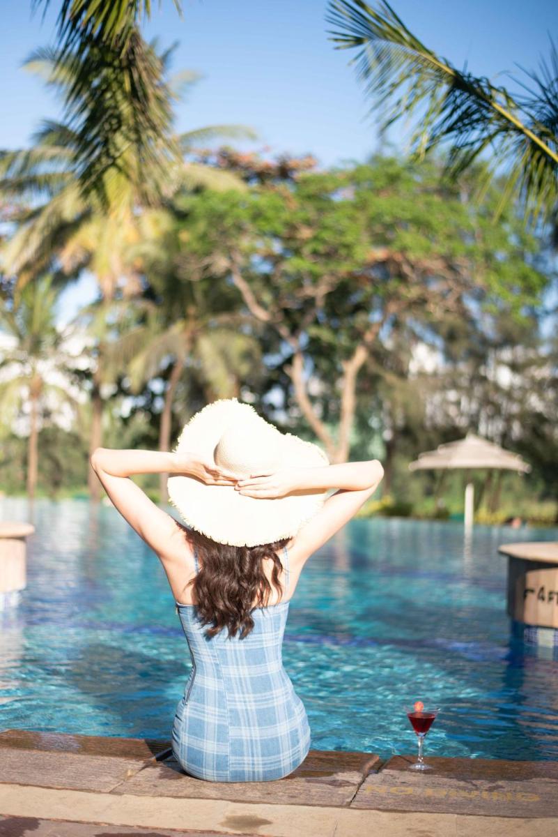 a woman in a hat sitting next to a pool at The Westin Mumbai Powai Lake in Mumbai