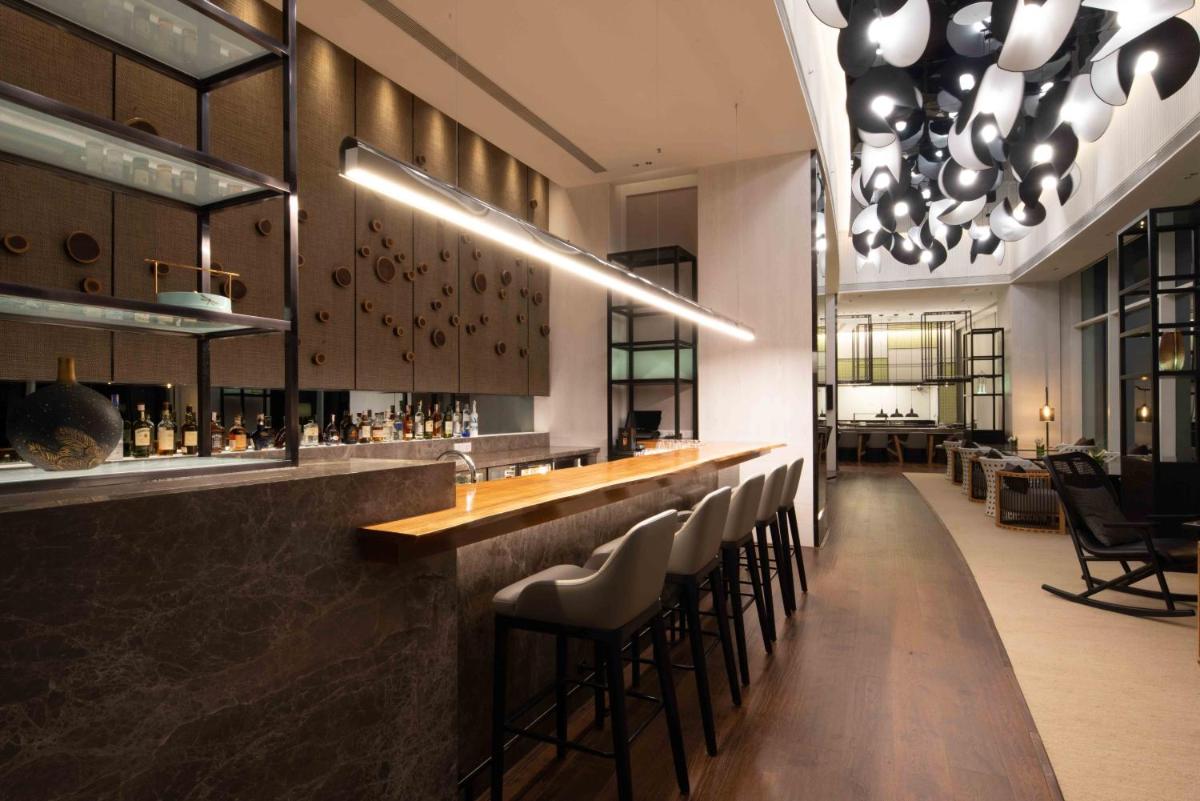 a bar with a row of stools in a restaurant at The Westin Mumbai Powai Lake in Mumbai