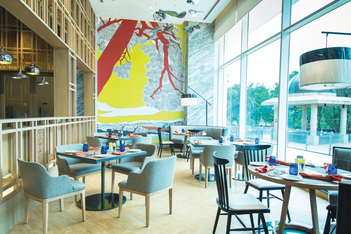 a restaurant with tables and chairs and windows at The Westin Mumbai Powai Lake in Mumbai