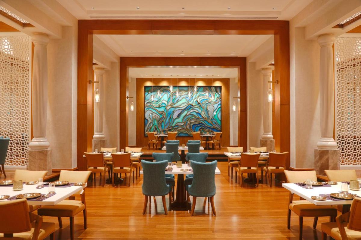 a restaurant with tables and chairs and a painting on the wall at The Westin Mumbai Powai Lake in Mumbai