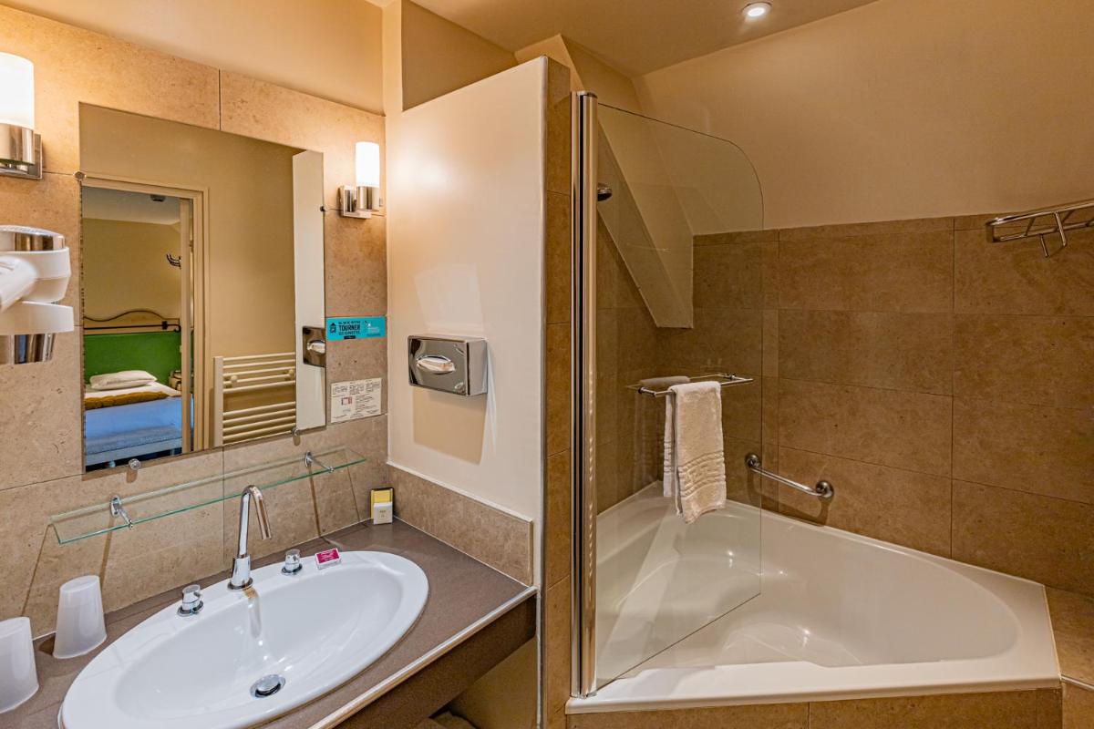 une salle de bain avec une baignoire et un lavabo dans l'établissement Logis Hostellerie des Clos et restaurant Bistrot des grands crus, à Chablis 51 autres photos