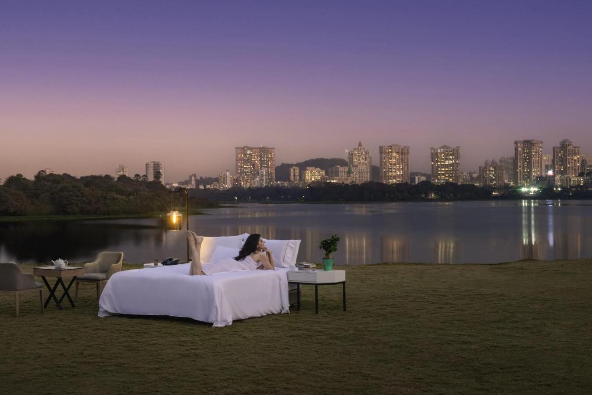 a woman laying in a bed in front of a lake at The Westin Mumbai Powai Lake in Mumbai a woman laying in a bed in front of a lake at The Westin Mumbai Powai Lake in Mumbai