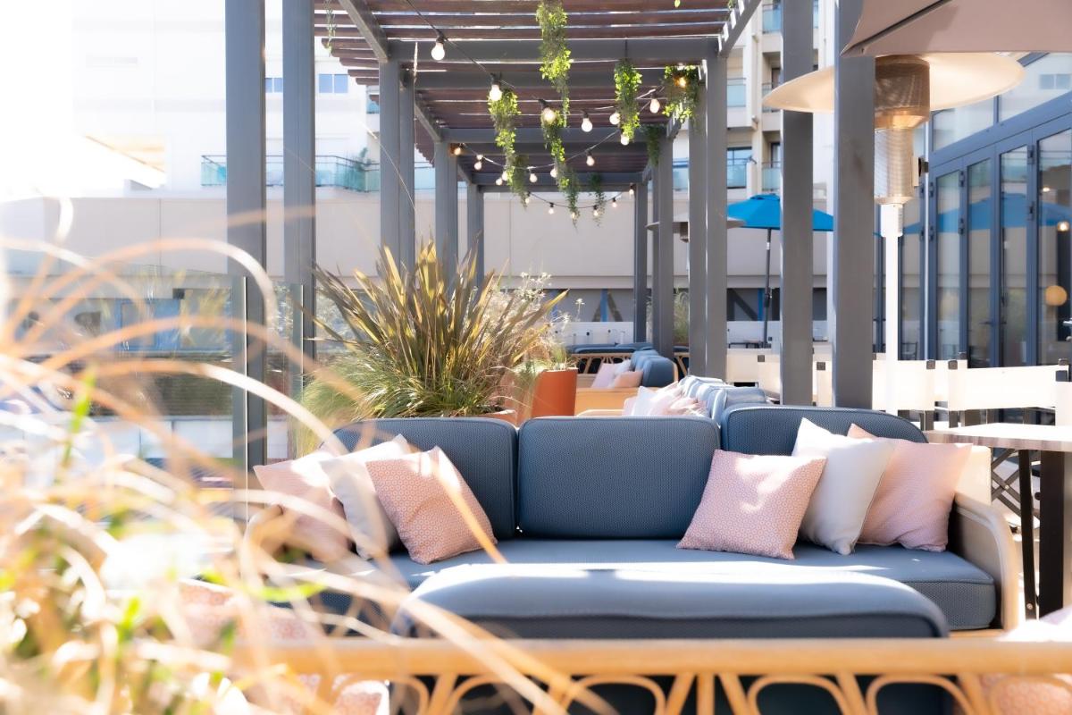 un canapé bleu assis sur une terrasse avec des oreillers dans l'établissement Hôtel Mar I Cel & Spa, à Canet