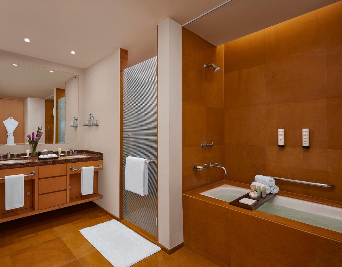 a bathroom with a shower and a tub and a sink at Grand Hyatt Mumbai Hotel and Residences in Mumbai