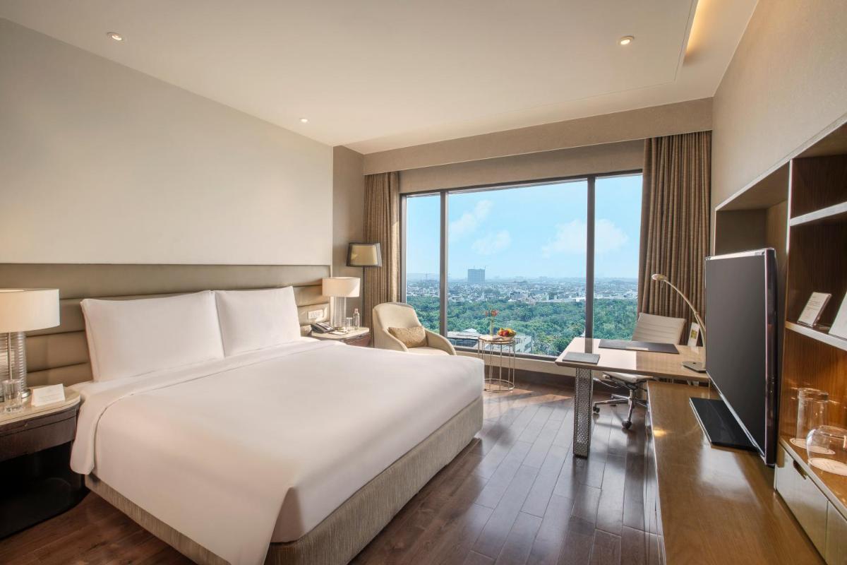a hotel room with a bed and a desk and a television at The Leela Ambience Convention Hotel Delhi in New Delhi