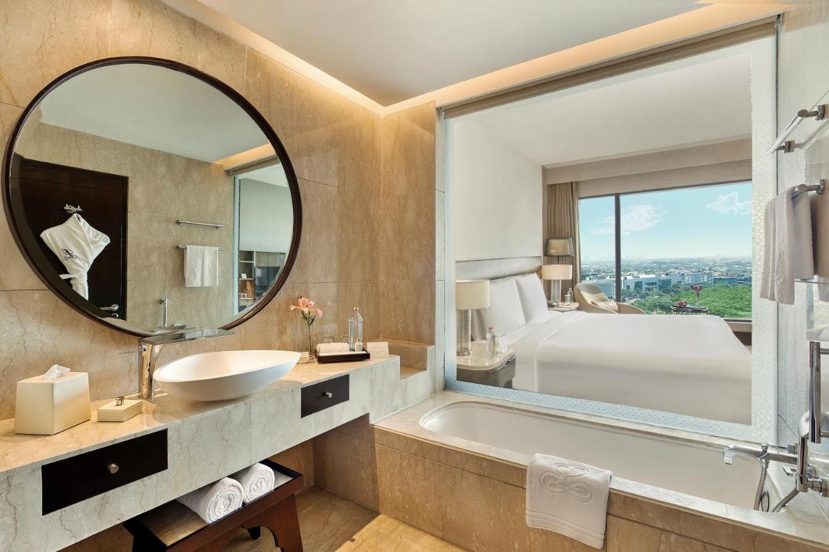 a bathroom with a tub and a sink and a mirror at The Leela Ambience Convention Hotel Delhi in New Delhi