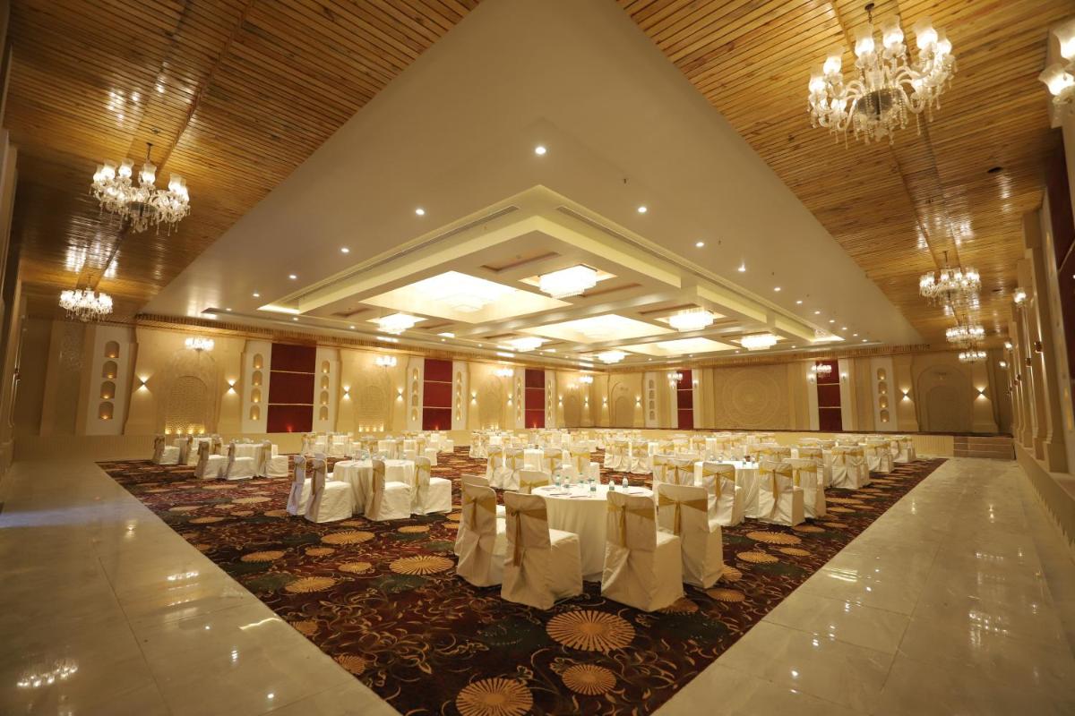 a banquet hall with white tables and chairs and chandeliers at Essentia Luxury Resort & Spa Udaipur in Udaipur
