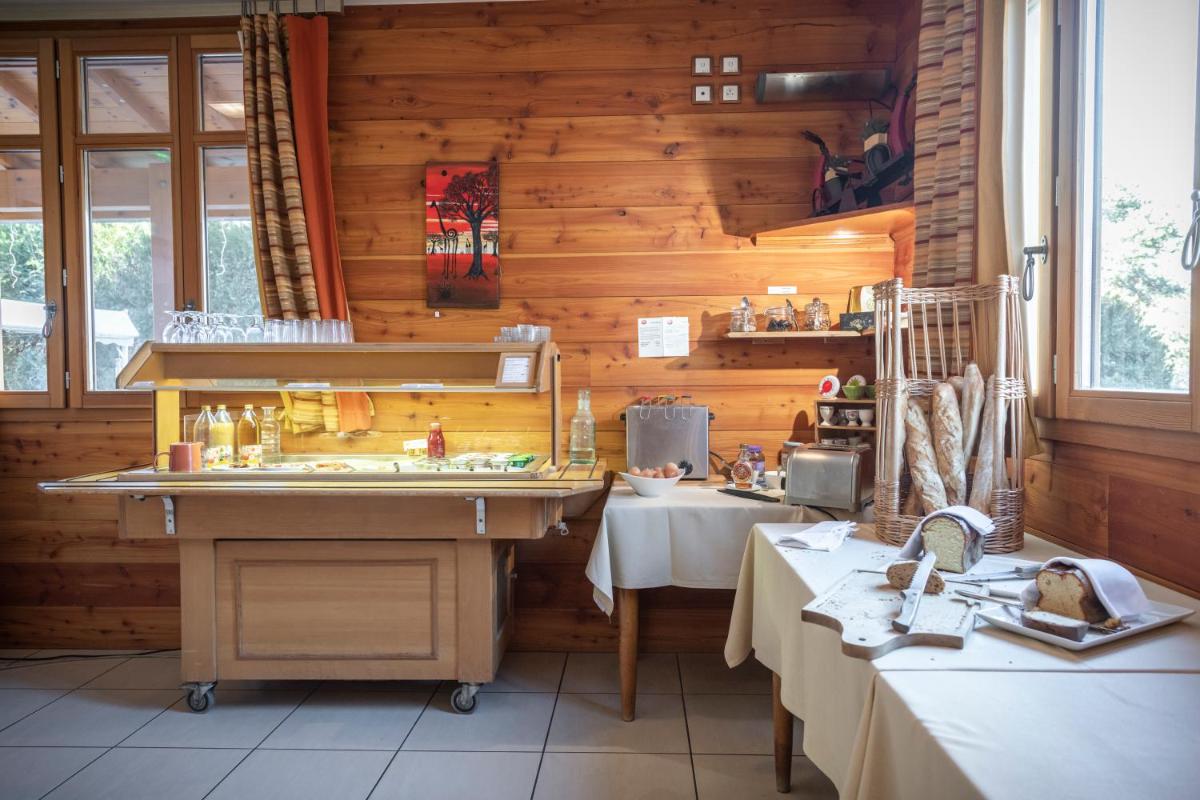 une cuisine avec des murs et des tables en bois dans une pièce dans l'établissement Logis Hôtel Les Peupliers, à Baratier