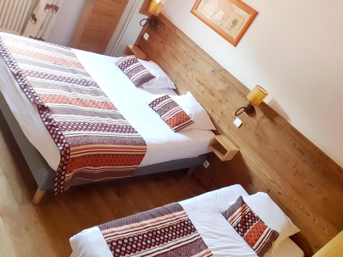 une chambre avec deux lits et un parquet dans l'établissement Logis Hôtel Les Peupliers, à Baratier