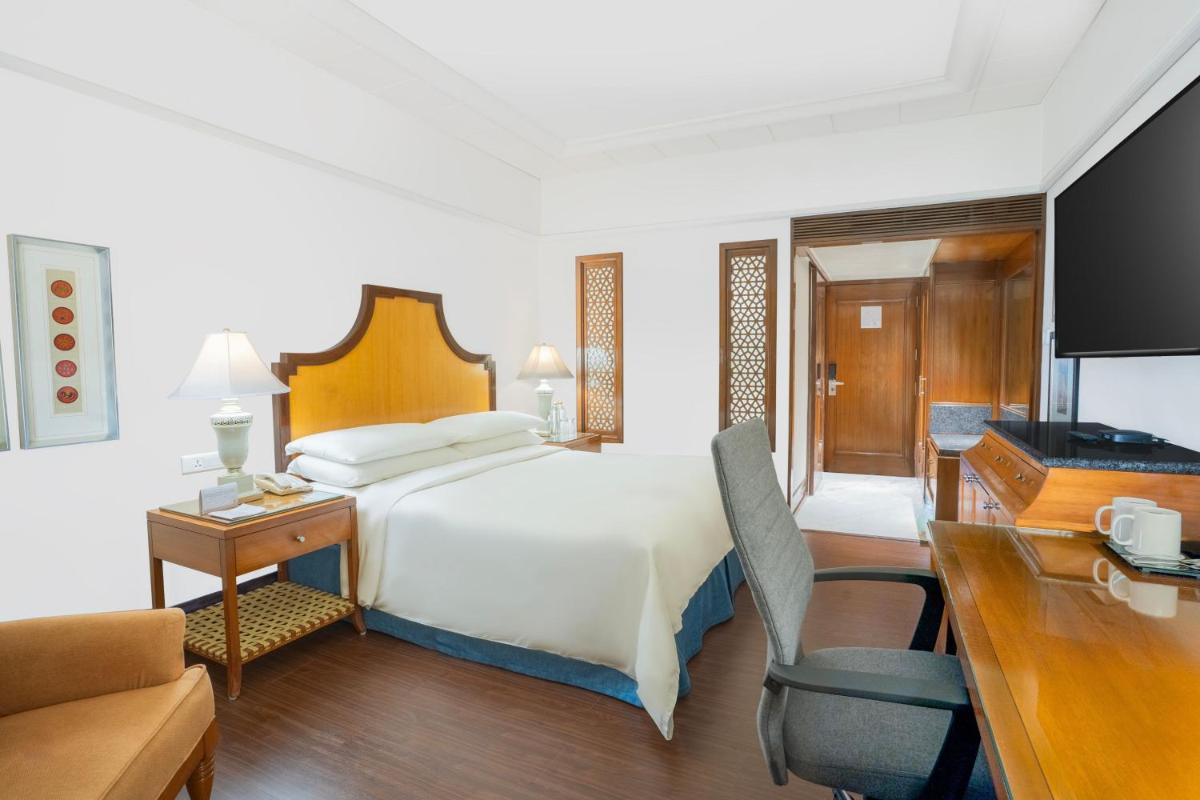 a hotel room with a bed and a desk and a television at Hyderabad Marriott Hotel & Convention Centre in Hyderabad