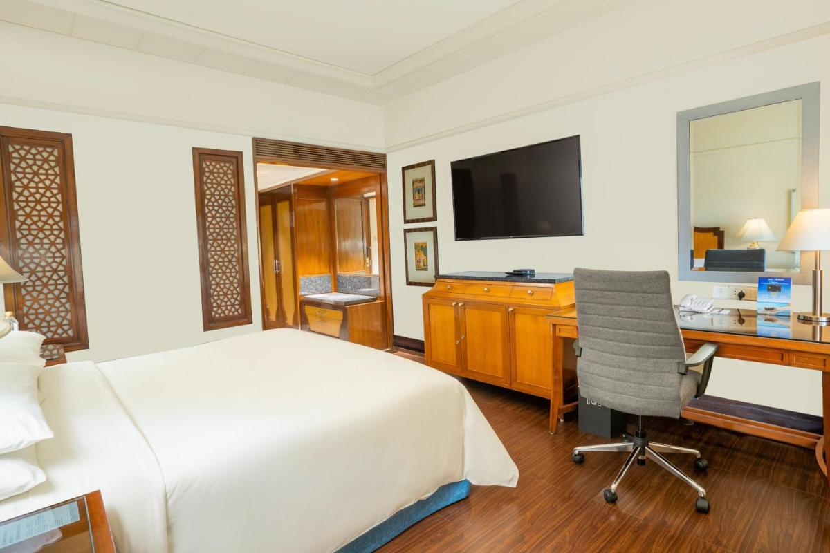 a bedroom with a bed and a desk and a television at Hyderabad Marriott Hotel & Convention Centre in Hyderabad