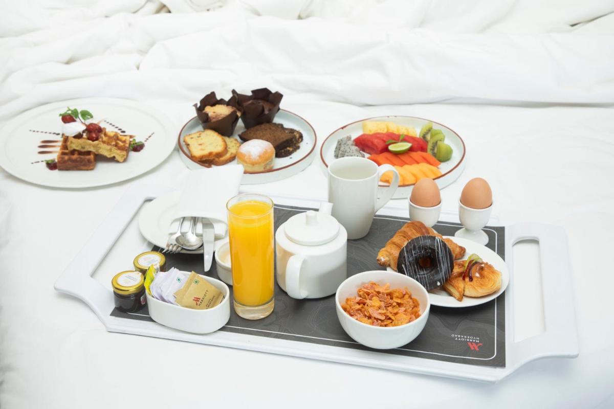 a tray of breakfast foods on a bed at Hyderabad Marriott Hotel & Convention Centre in Hyderabad