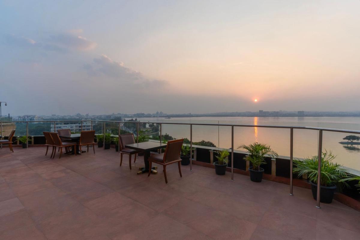 a balcony with tables and chairs and a view of the water at Hyderabad Marriott Hotel & Convention Centre in Hyderabad