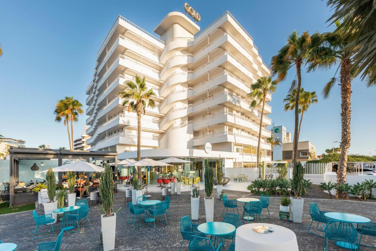 un hotel con mesas, sillas y palmeras en Gold By Marina - Adults only, en Playa del Inglés