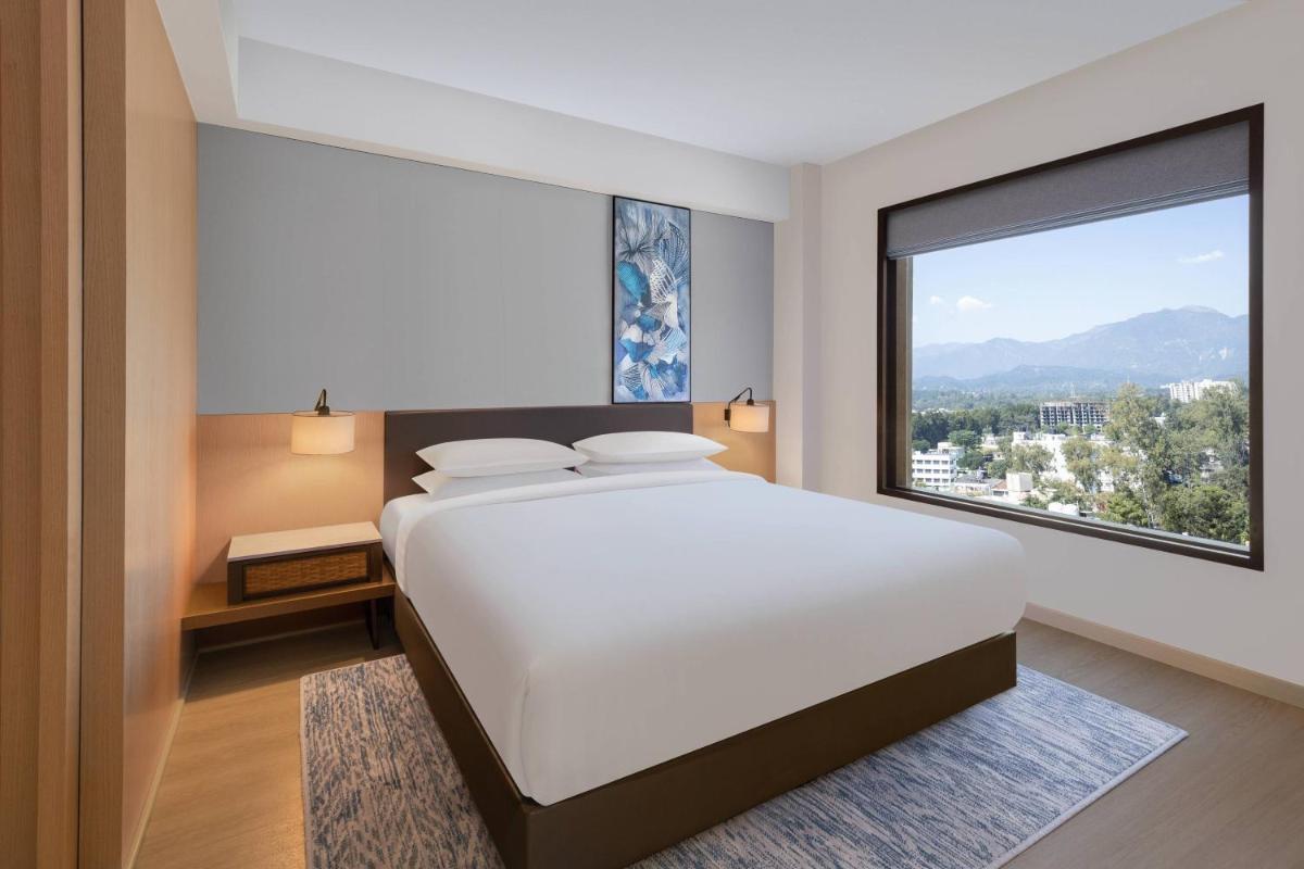 a bedroom with a large bed and a large window at Fairfield by Marriott Dehradun in Dehradun