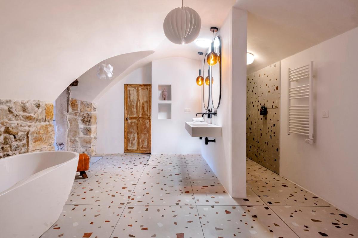 La salle de bains est pourvue d'une baignoire, d'un lavabo et d'un mur. dans l'établissement DODO etc, à Nyons