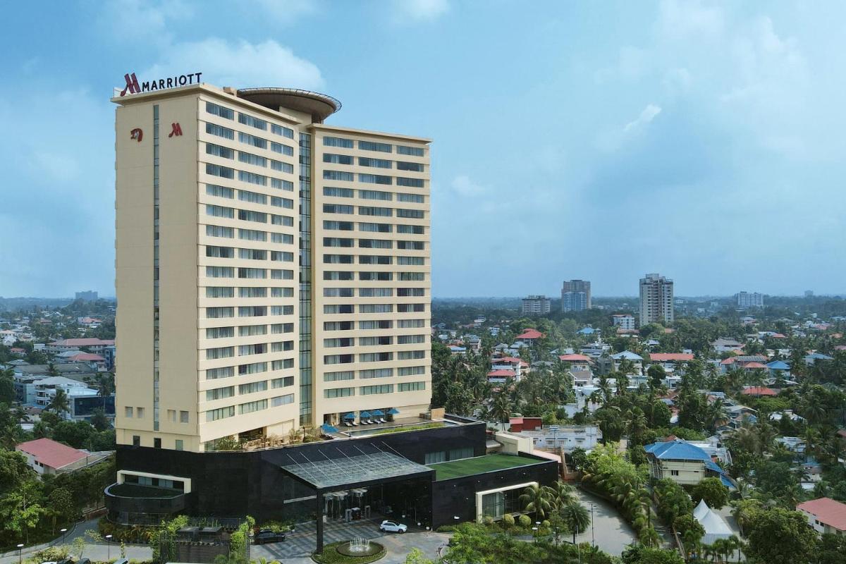 a tall hotel building with a city in the background at Kochi Marriott Hotel in Cochin