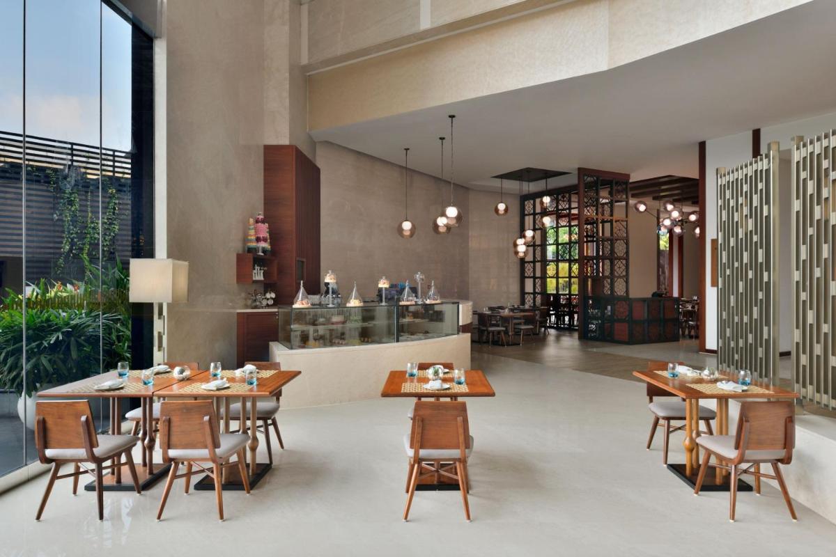 a dining room with wooden tables and chairs at Kochi Marriott Hotel in Cochin