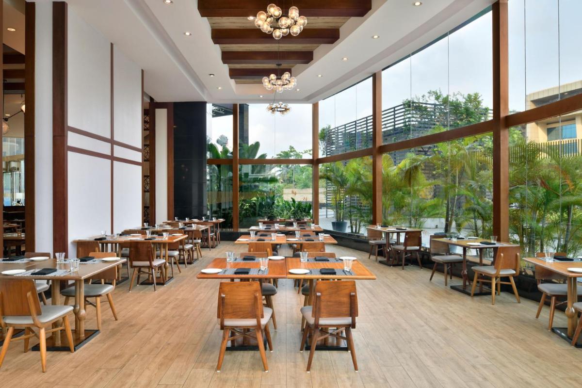 a restaurant with tables and chairs and large windows at Kochi Marriott Hotel in Cochin