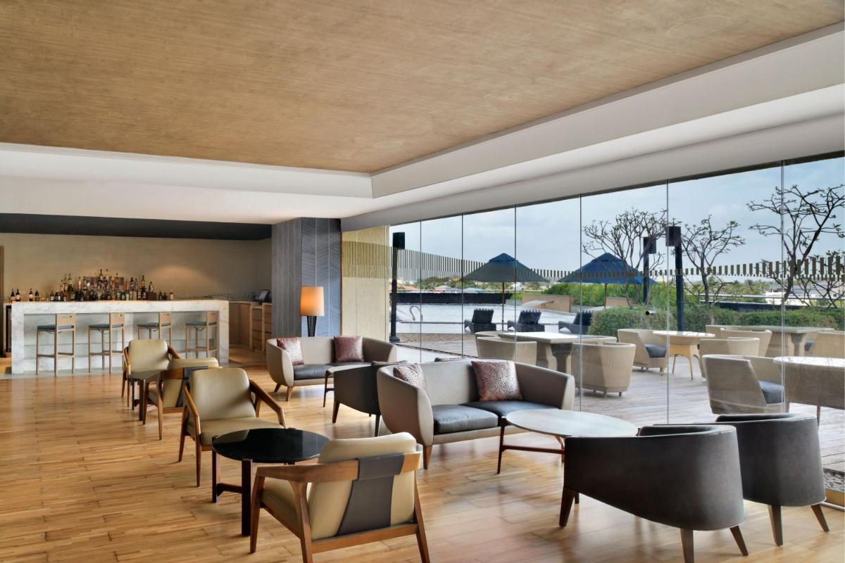 a lobby with chairs and tables and a large window at Kochi Marriott Hotel in Cochin