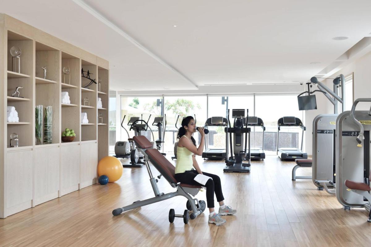 a woman sitting on a treadmill in a gym at Kochi Marriott Hotel in Cochin