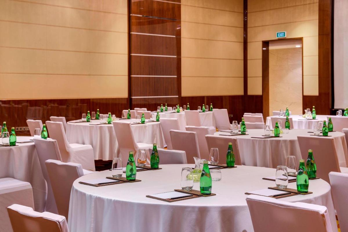 a room with white tables and chairs with green bottles at Kochi Marriott Hotel in Cochin