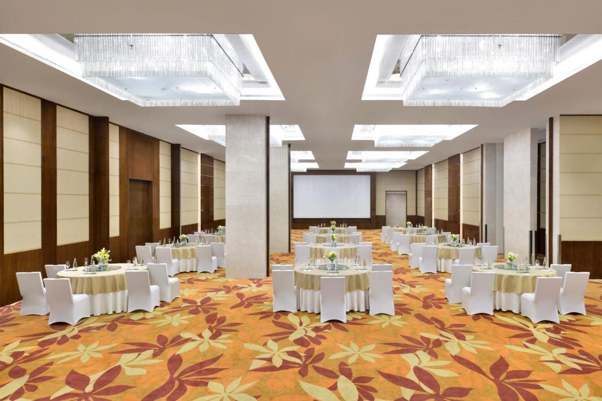 a banquet hall with white tables and a projection screen at Kochi Marriott Hotel in Cochin