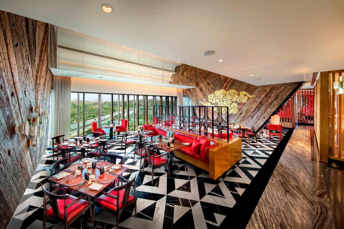 a restaurant with red chairs and tables in a room at ITC Kohenur, a Luxury Collection Hotel, Hyderabad in Hyderabad