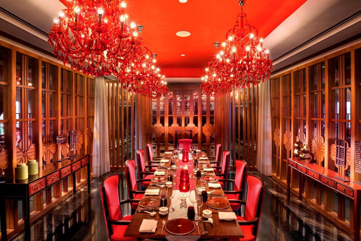 a long table in a restaurant with red chairs and chandeliers at ITC Kohenur, a Luxury Collection Hotel, Hyderabad in Hyderabad