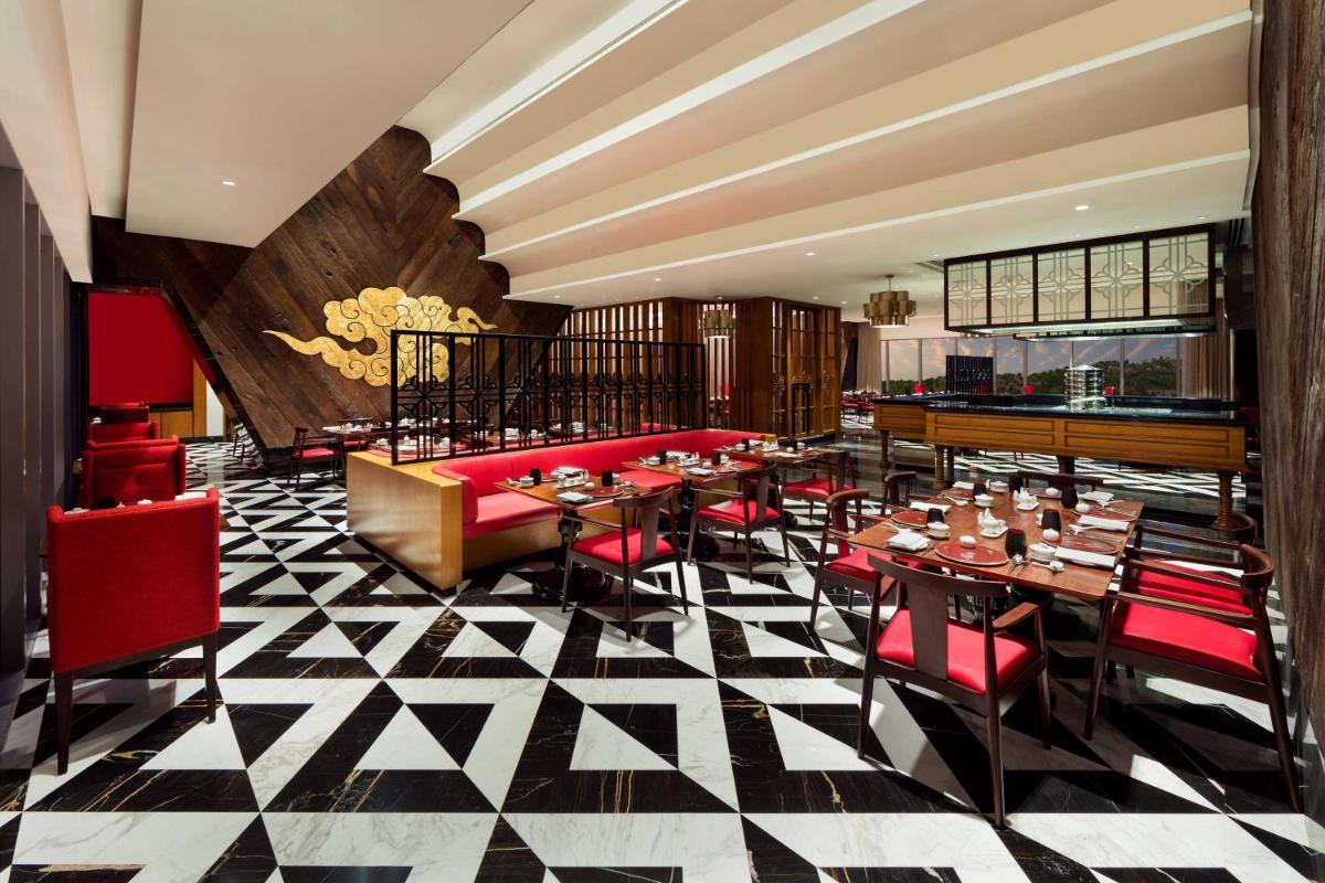 a restaurant with tables and red chairs in a room at ITC Kohenur, a Luxury Collection Hotel, Hyderabad in Hyderabad