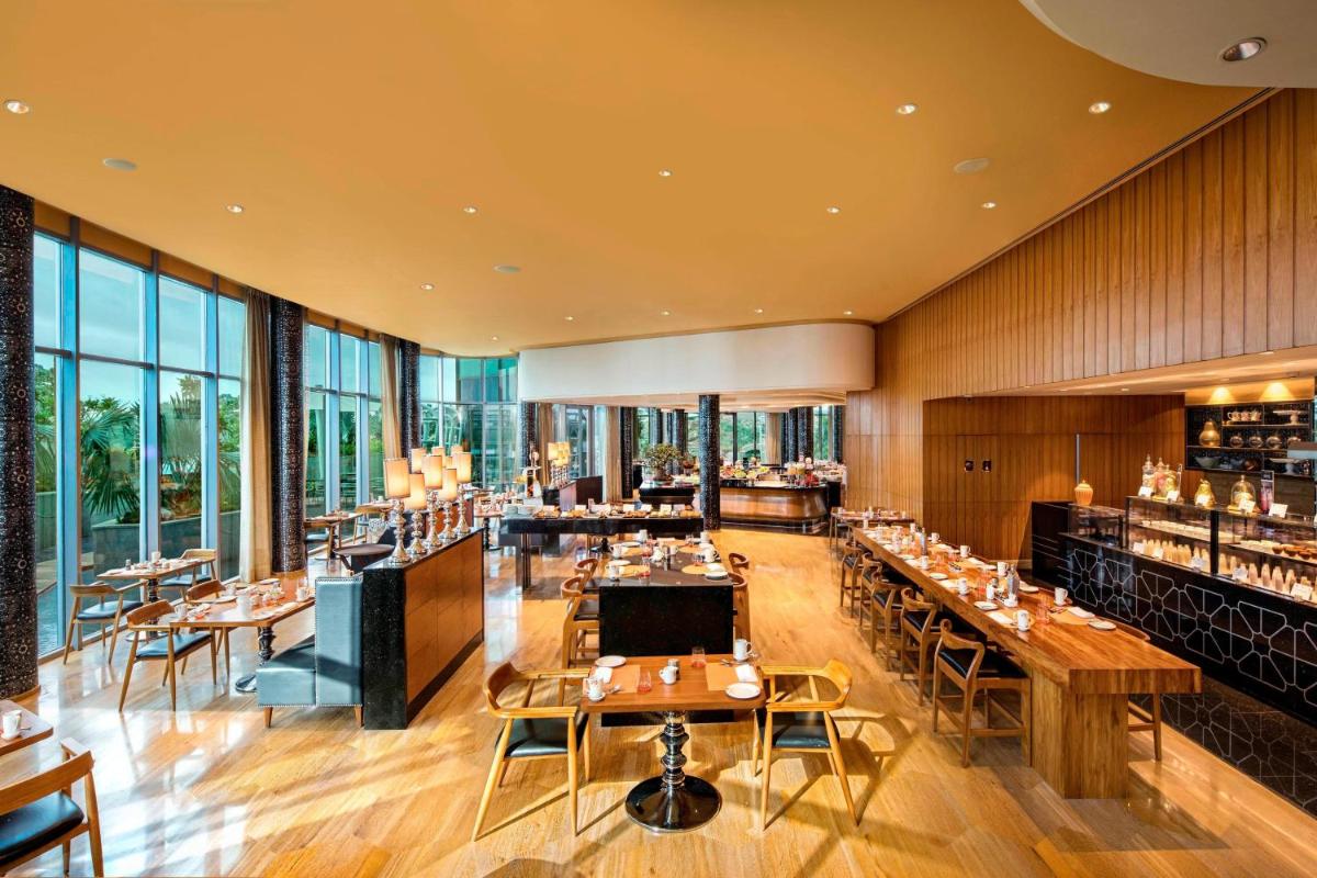 a restaurant with tables and chairs and windows at ITC Kohenur, a Luxury Collection Hotel, Hyderabad in Hyderabad