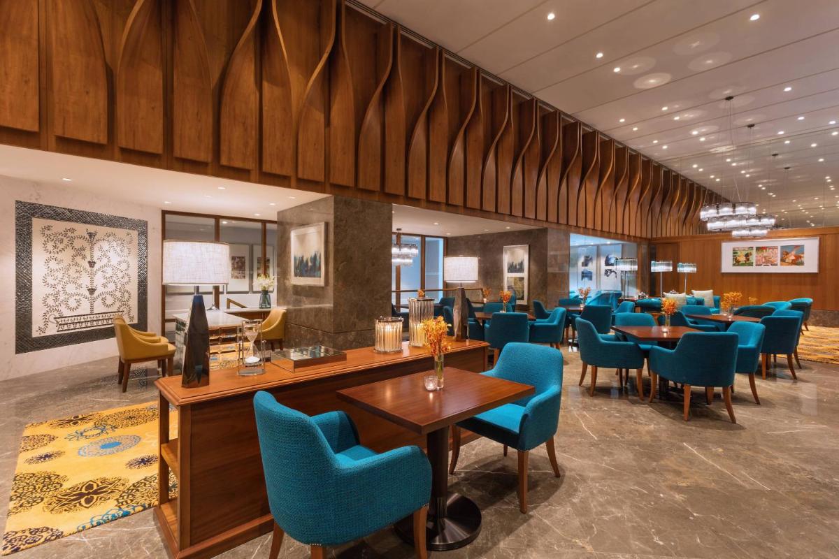 a dining room with blue chairs and tables at ITC Kohenur, a Luxury Collection Hotel, Hyderabad in Hyderabad