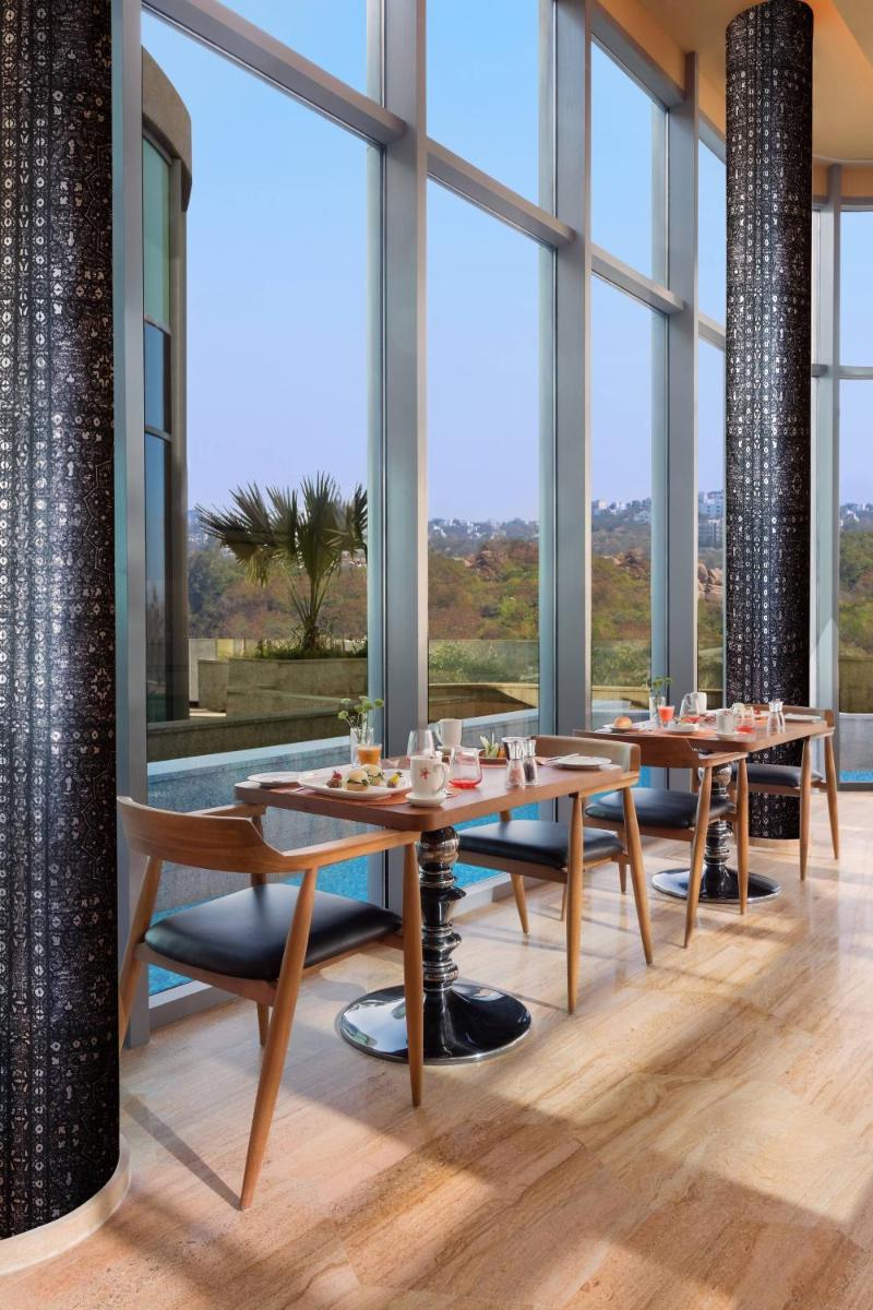 a dining room with tables and large windows at ITC Kohenur, a Luxury Collection Hotel, Hyderabad in Hyderabad