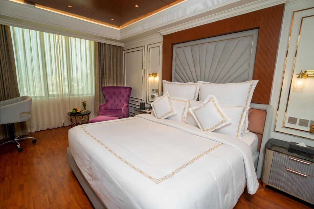 a bedroom with a large white bed and a purple chair at The Accord Metropolitan in Chennai