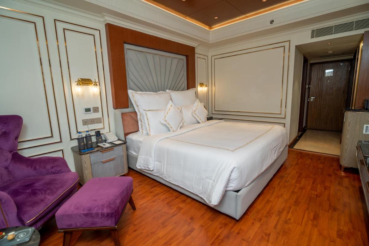 a bedroom with a large white bed and a purple chair at The Accord Metropolitan in Chennai