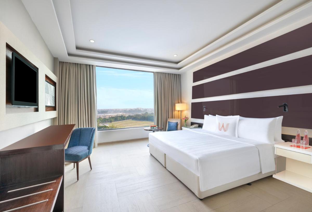 a hotel room with a large white bed and a desk at Welcomhotel by ITC Hotels, Dwarka, New Delhi in New Delhi a hotel room with a large white bed and a desk at Welcomhotel by ITC Hotels, Dwarka, New Delhi in New Delhi
