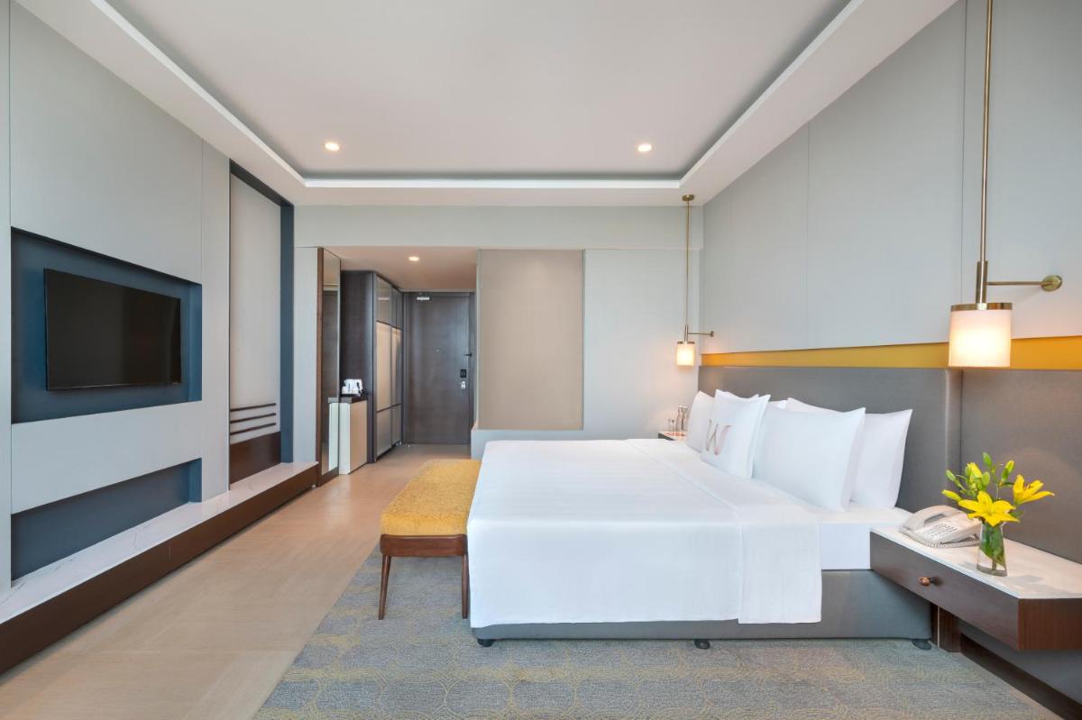 a bedroom with a large white bed and a tv at Welcomhotel by ITC Hotels, Dwarka, New Delhi in New Delhi a bedroom with a large white bed and a tv at Welcomhotel by ITC Hotels, Dwarka, New Delhi in New Delhi