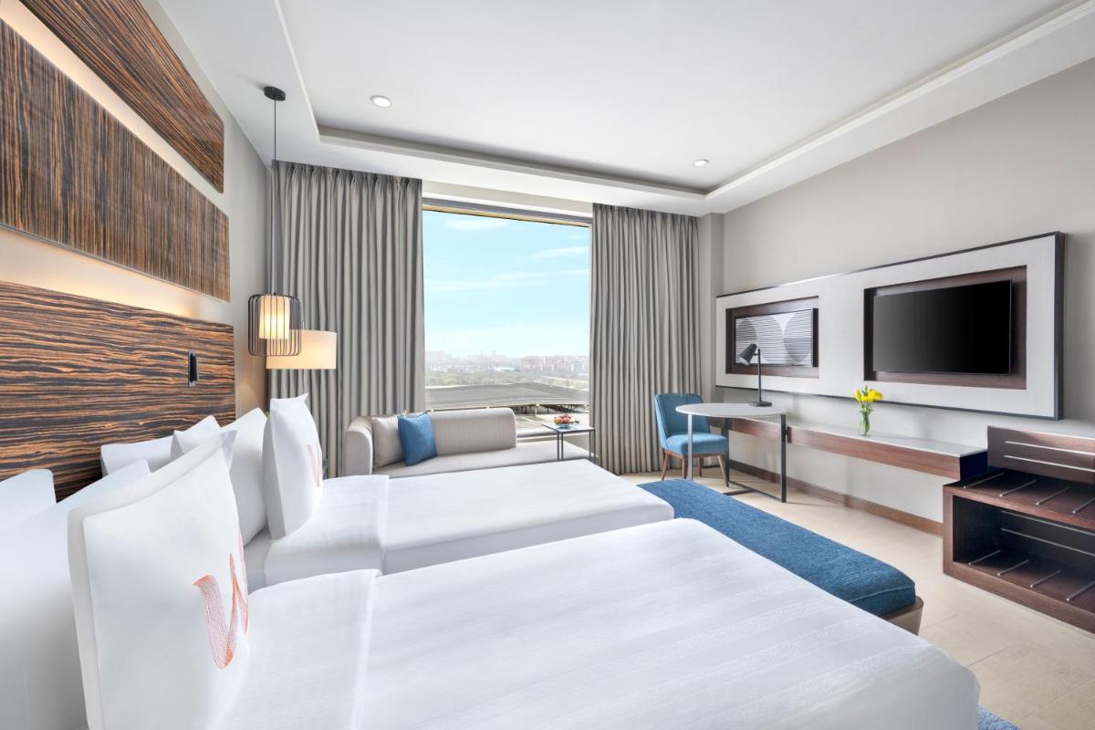 a hotel room with two beds and a flat screen tv at Welcomhotel by ITC Hotels, Dwarka, New Delhi in New Delhi a hotel room with two beds and a flat screen tv at Welcomhotel by ITC Hotels, Dwarka, New Delhi in New Delhi