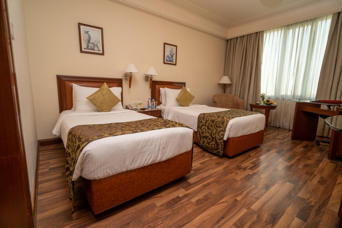 a hotel room with two beds and a desk at The Accord Metropolitan in Chennai